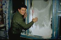 Man draping material over window to keep heat in - a cold night ahead